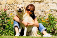 Une femme assise dans l’herbe avec son chien entre ses jambes