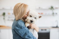 Une femme tenant dans ses bras un chien en le câlinant