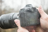 Un photographe tenant son appareil photo mouillé par la pluie