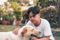 Un jeune Philippin en train de caresser un chien adulte