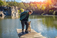 Un homme accompagné de son Labrador Retriever se tenant sur un ponton, au bord d'un lac