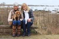 Deux femmes assises sur un banc au bord d'un lac, avec un chien sur les genoux