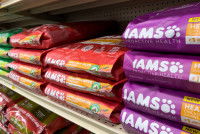 Des sacs de croquettes pour chien empilés sur une étagère dans un supermarché