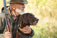 Un chien noir en train d'être enlacé par un chasseur