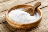 Du bicarbonate de sodium dans un bol en bois avec une cuillère