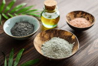 Des poudres d'argile verte, noire et rose dans des coupelles