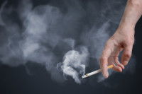 Un homme fume une cigarette sur un fond noir