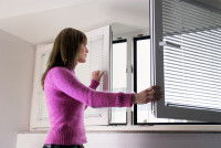 Une femme ouvre les fenêtres pour aérer le logement