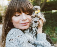 Une jeune femme serre son petit chien contre elle
