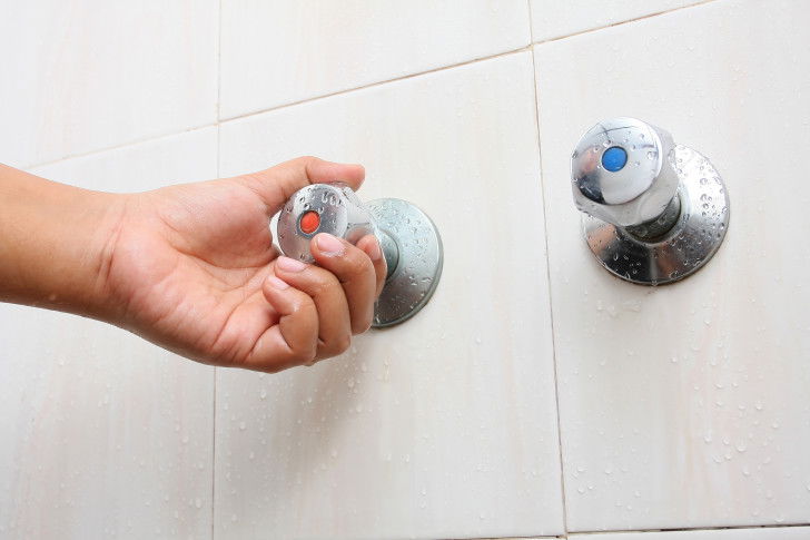 Une femme tourne le robinet d'eau chaude
