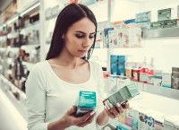 Une femme dans une pharmacie hésite entre deux produits
