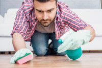 Un homme nettoie et désinfecte le sol de son appartement