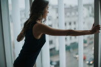 Une jeune femme ouvre les fenêtres de son salon