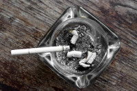 Un cendrier contenant des mégots sur une table en bois