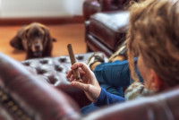 Une femme fume un cigare dans son canapé devant son chien