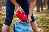 Une femme met la trousse de secours dans son sac à dos