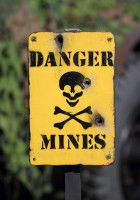 Panneau jaune avec une tête de mort signalant un danger avec des mines