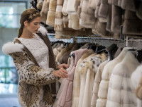 Une femme regardant des manteaux de fourrure dans un magasin