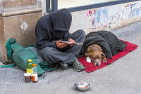 Un homme sans-abri assis dans la rue avec un chien allongé à ses côtés