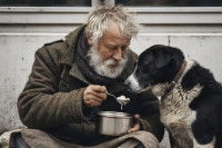 Un homme sans-abri donnant une cuillère de nourriture à son chien