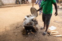 Un cuisinier africain prépare du chien dans une marmite