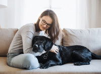 Une femme et son chien noir sur le canapé
