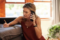 Une femme au téléphone note des informations sur un carnet