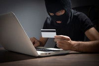 Un escroc fait une arnaque en ligne avec un ordinateur et une carte bleue