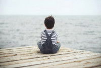 Un enfant assis sur un ponton observe l'horizon