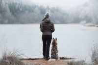Une femme et son Husky face à un lac en hiver