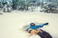 Une personne et un chien allongés dans la neige.