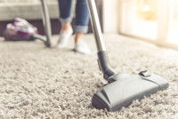 Une personne passant l'aspirateur sur un tapis dans un appartement.