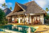 Vue extérieure d'une villa individuelle ayant des fenêtres en bois et un toit de chaume, avec une terrasse et une piscine.