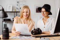 Une photographe et sa cliente, assises côte à côte et regardant une feuille de papier