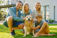 Les membres d'une famille et leur Golden Retriever posant pour une photo dans leur jardin