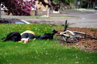 Une femme et un Labrador noir allongés sur l'herbe près d'un vélo renversé