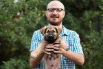 Un chiot Berger Allemand tenu dans les mains d'un homme portant des lunettes