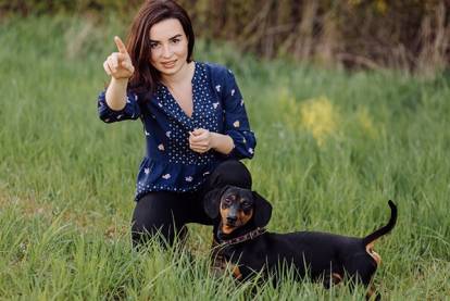 Un Teckel semblant suivre une séance d'éducation avec sa maîtresse