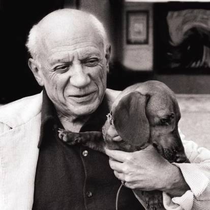 Pablo Picasso souriant et tenant un Teckel dans ses bras