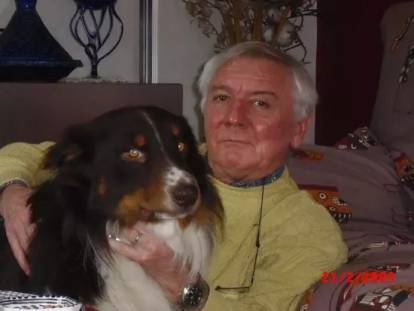 Un Berger Australien allongé à côté d'une personne agée