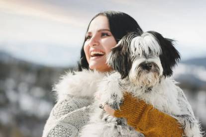 Un Terrier du Tibet tenu dans les bras d'une femme 