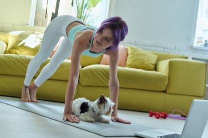 Un Yorkshire Terrier allongé sur un tapis de yoga alors que sa maîtresse est en train de faire ses exercices au-dessus de lui