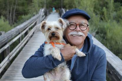 Un homme âgé portant un Yorkshire Terrier dans ses bras alors qu'il traverse un pont