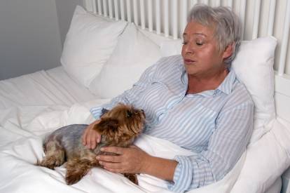 Une femme âgée alitée avec un Yorkshire Terrier