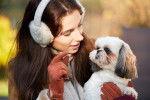 Une femme tenant un Shih Tzu dans les bas et levant un doigt