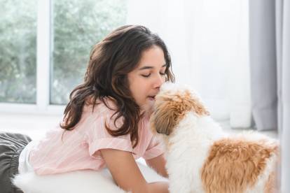 Un Shih Tzu et une jeune femme allongée se faisant face et partageant un moment affectueux