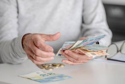 Une personne âgée en train de compter des billets