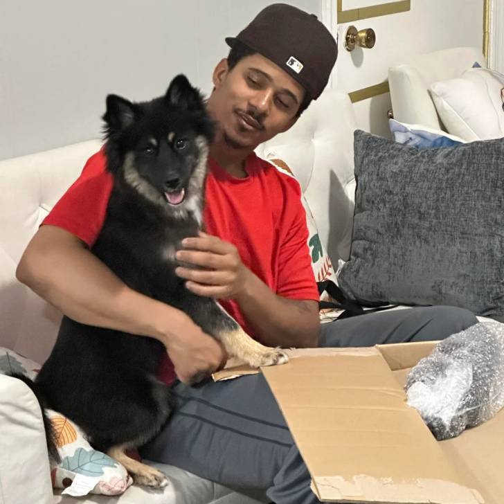 Un Husky Sibérien assis sur un canapé à côté d'un jeune homme