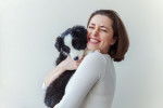 Une femme en train de sourire en tenant dans ses bras un chiot Border Collie