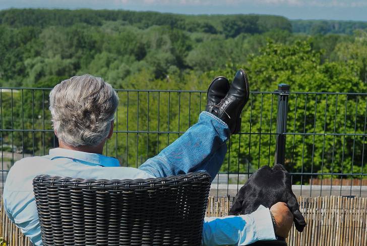 Cane Corso assis à côté d'un vieil homme assis sur une chaise et admirant le paysage